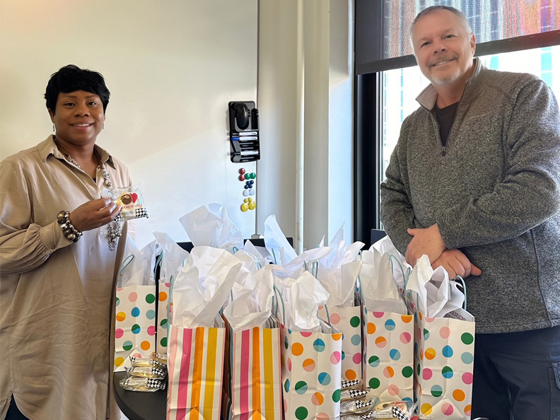 Two people posing with gift bags.
