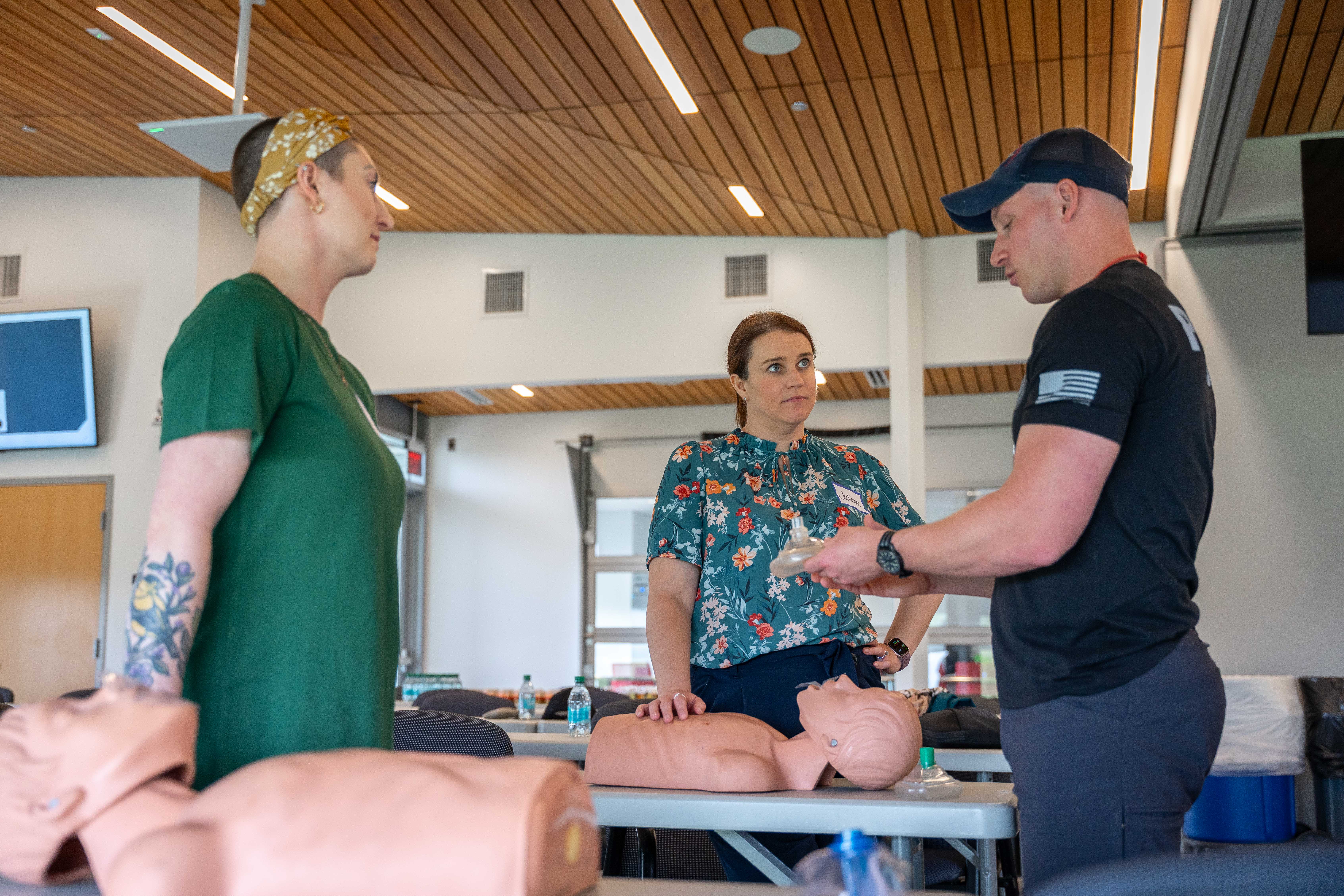 Two women are seen learning how to perform CPR on a mannequin.