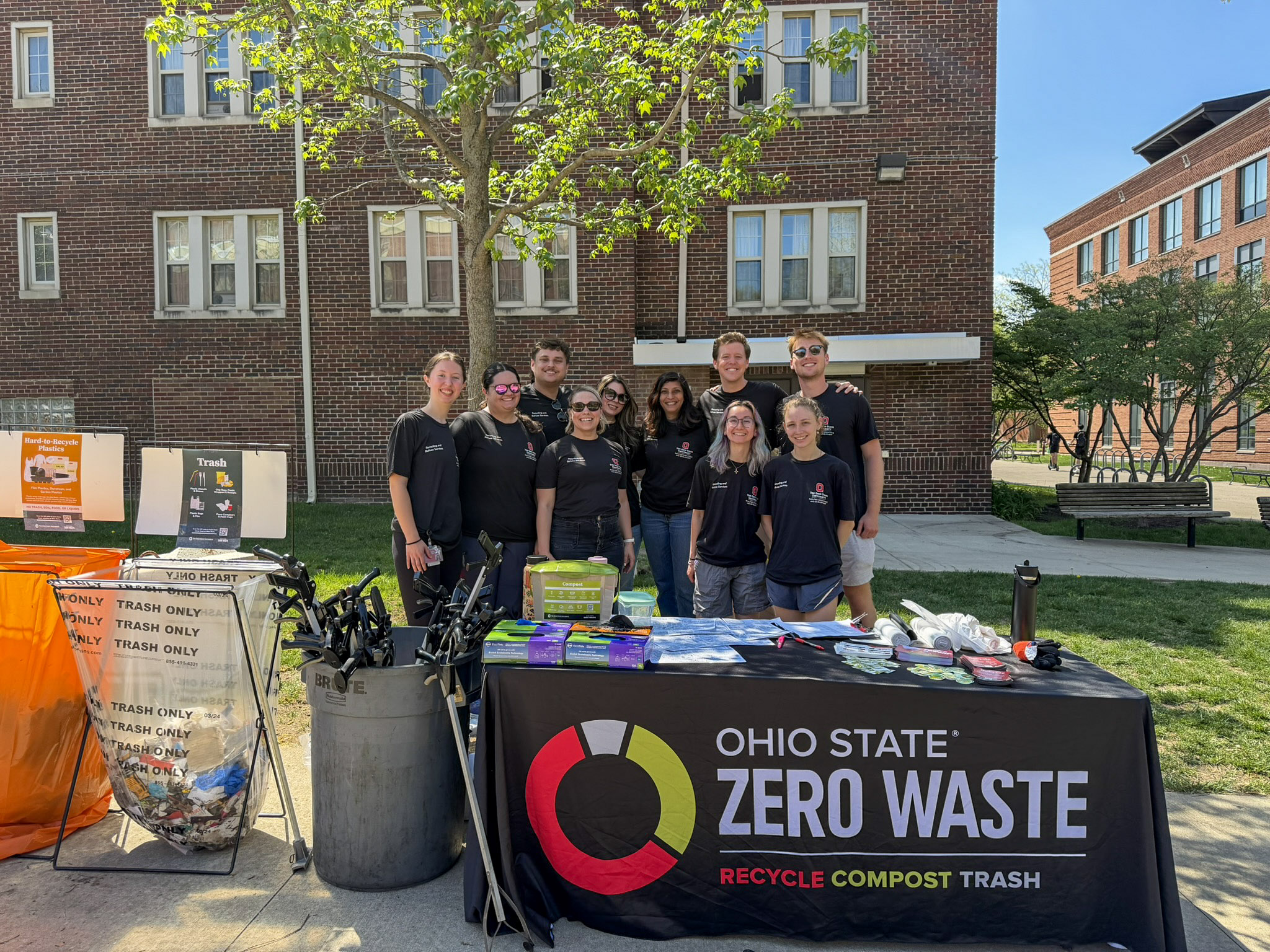 A group of people stand smiling in front of an Ohio State Zero Waste banner.