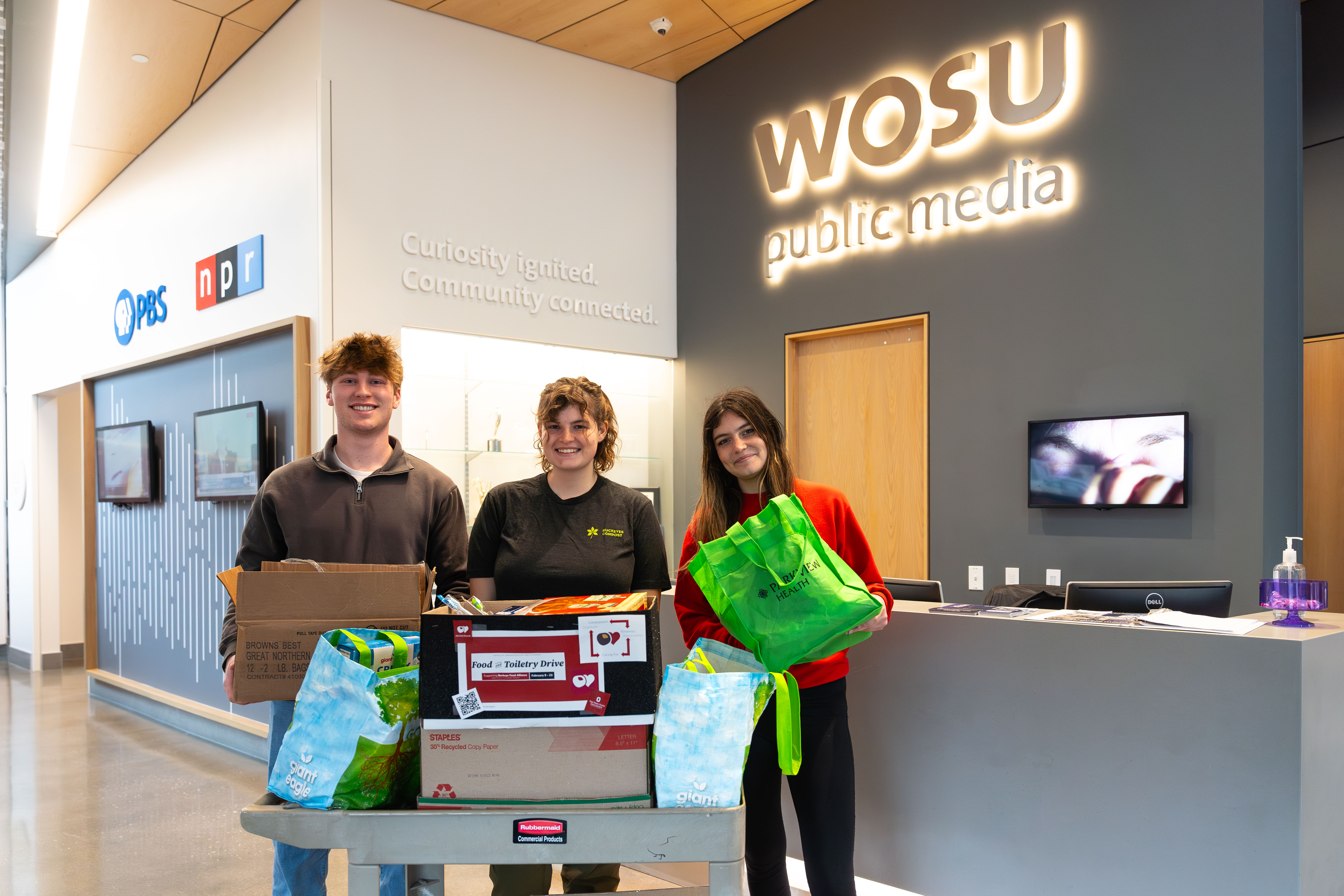 three people holding food and toiletry donations at WOSU