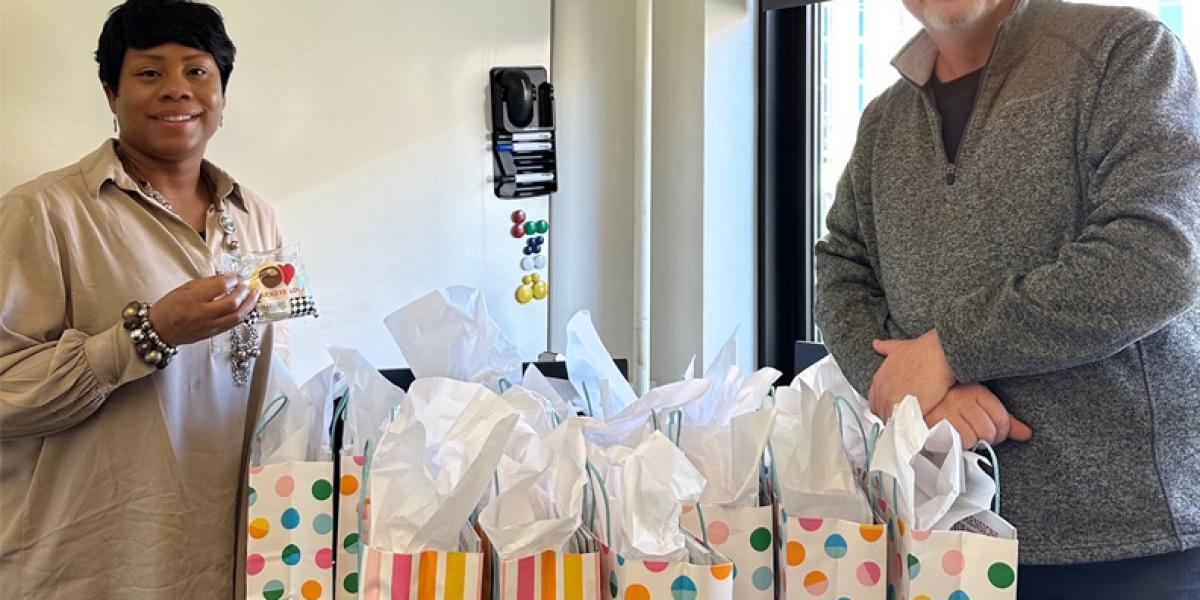 Two people posing with gift bags.