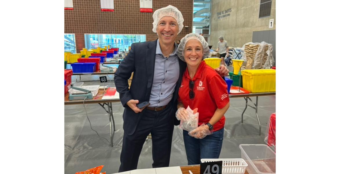 Chris Kabourek and Nicole Holman smile at the camera while at the meal packing event. 