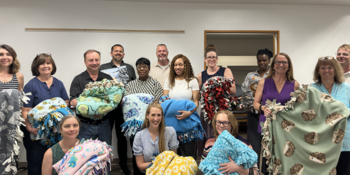 group of people holding fleece blankets